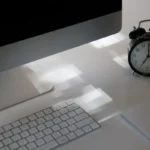 Area kerja produktif dengan komputer dan jam analog yang menunjukkan waktu kerja